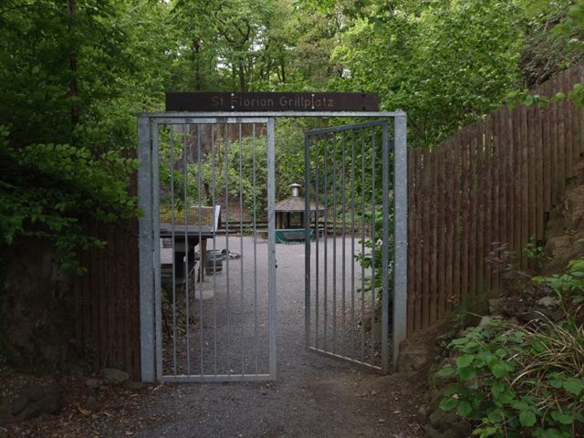 Eingangstor zum St. Florian Grillplatz zwischen Holzzaun und Grün